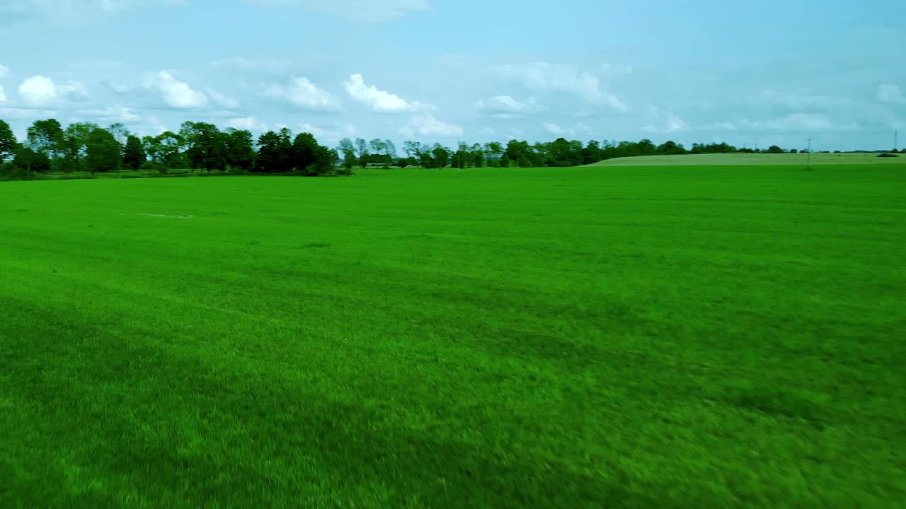 Images aériennes d'un champ d'herbe, d'une pelouse verte et d'un ciel bleu, paysage naturel de village, image cinématographique capturée par drone.