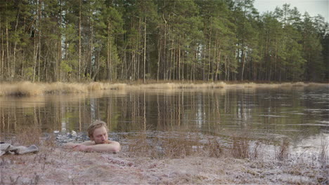 wide shot - an ice bather slips into the ice hole he has made in the frozen lake