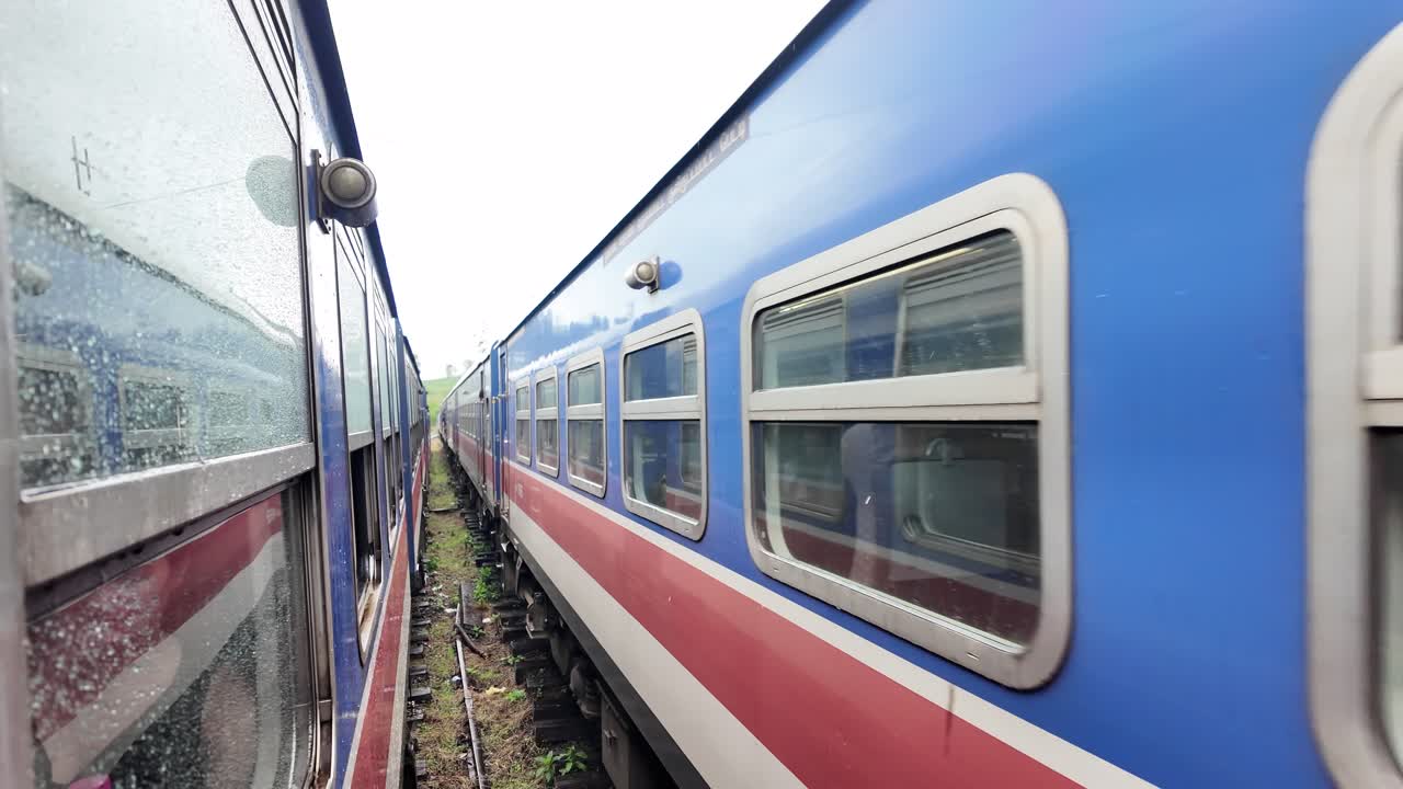 Blue train passes another on the tracks at the Great Western station in Talawakelle, Sri Lanka. Slow Motion