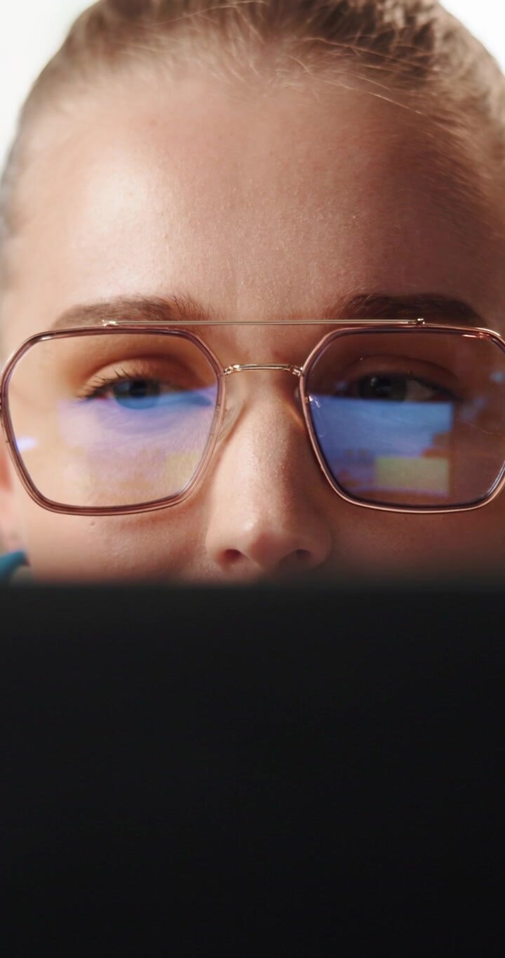 Primo piano di una giovane donna con gli occhiali che guarda lo schermo del laptop