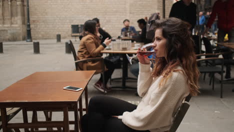 Una-Joven-Sentada-En-Un-Café-Bebiendo-Una-Copa-De-Vino-Tinto.