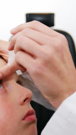 una optometra que pone gotas oculares en los ojos de un paciente joven