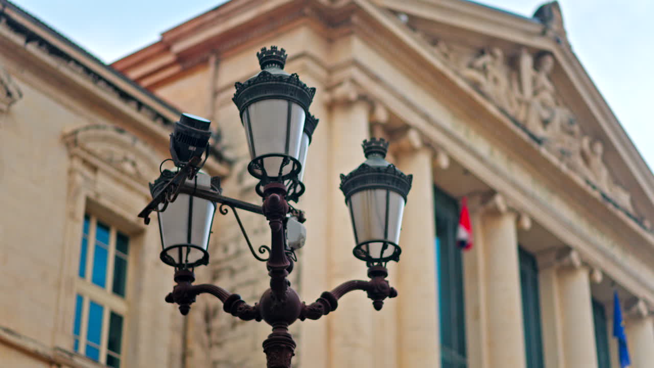 Close up of a street lamp with a blurred view of the Nice courthouse on the background