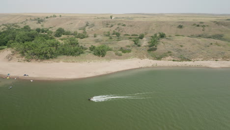 vista lateral aérea de lancha rápida navegando por la costa del lago, horizonte terrestre en segundo plano en el aterrizaje de saskatchewan, canadá