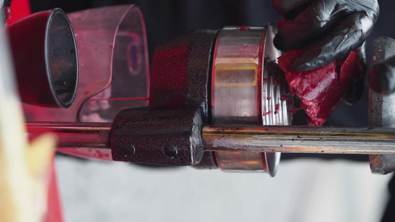 Close-up of a machine processing red fruits or vegetables