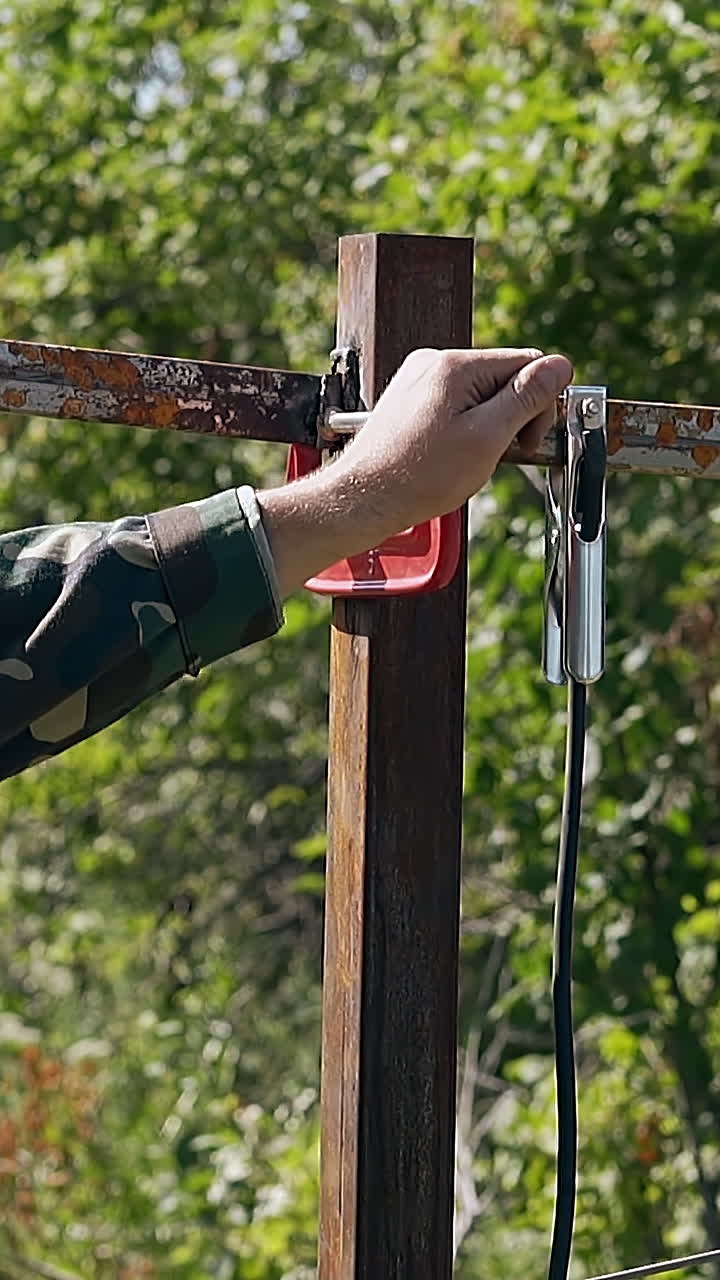 slow motion welder in mask on head takes away clamp from metal plank welded to fence pole in garden