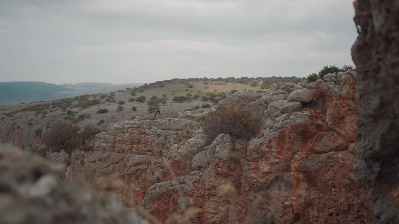 мужчина-пешеход идет по скалистой местности над обрывами в заповеднике нахаль амуд, израиль