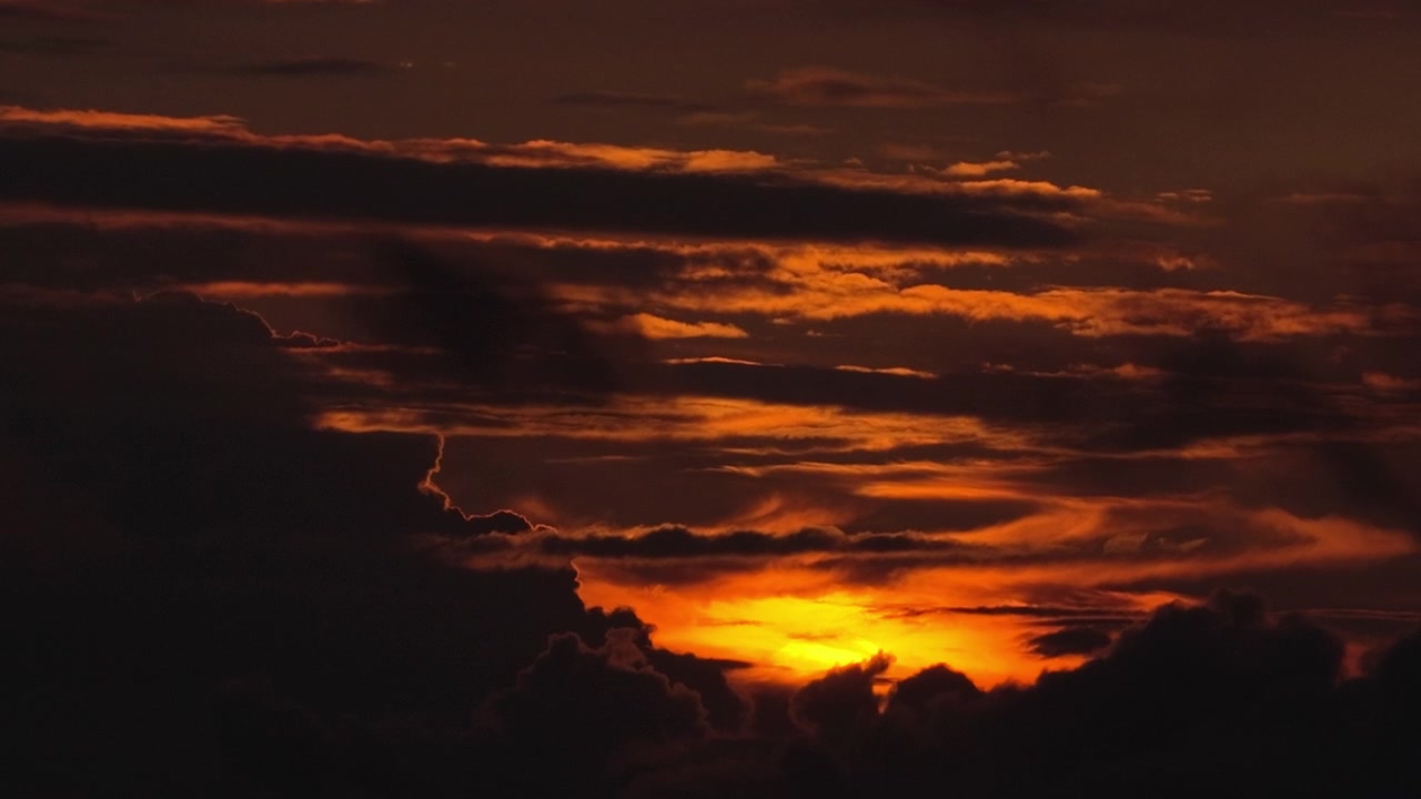 Drohnenaufnahme eines tief orangefarbenen und roten Sonnenuntergangs, der durch dichte Wolken über dem Meer leuchtet, Kreta, Griechenland