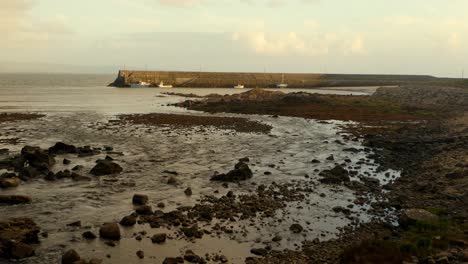 aerial shot of spiddal pier, connemara, as the drone glides backward over the flowing river meeting the ocean, revealing the expansive scene