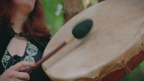 druid girl in a forest playing a shamanic drum detail close shot