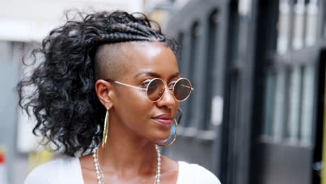 Moda-Joven-Mujer-Negra-Girando-Y-Mirando-A-La-Cámara-Sobre-Sus-Gafas-De-Sol-Redondas,-Cerrar