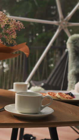 mesa de comedor con jarrón en la terraza de vidrio. espacio moderno con sillones esponjosos crea una atmósfera de relajación en el desayuno con una vista impresionante desde la terraza brillante