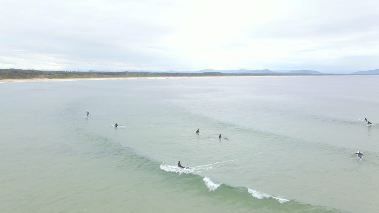turistas cabalgando sobre las grandes olas en la playa de scotts head en el estado australiano de nueva gales del sur