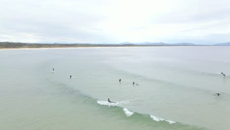 tourists riding on the big waves on the beach of scotts head in australian state of new south wales