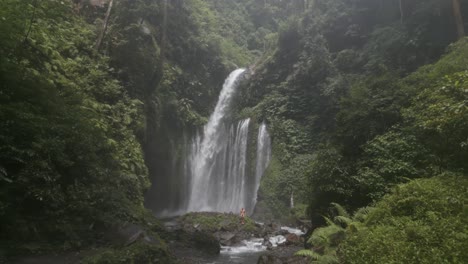 caucasian man alone at base of misty jungle tiu kelep waterfall lombok