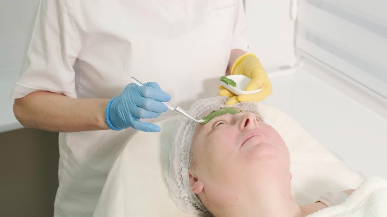 procedimientos profesionales de cuidado facial en la clínica de cosmetología moderna. aplicación de máscaras faciales