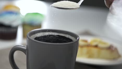 sugar crystals falling from tablespoon to cup of coffee - slow motion