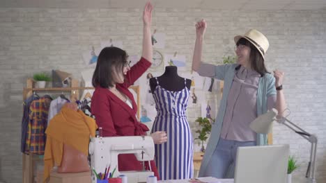 dos jóvenes diseñadores de moda positivos lanzan papeles de alegría de que han terminado el trabajo