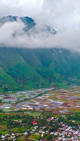 rainy cloudy formation timelapse over rice paddy agricultural fields in bali village, hills in background, aerial, vertical