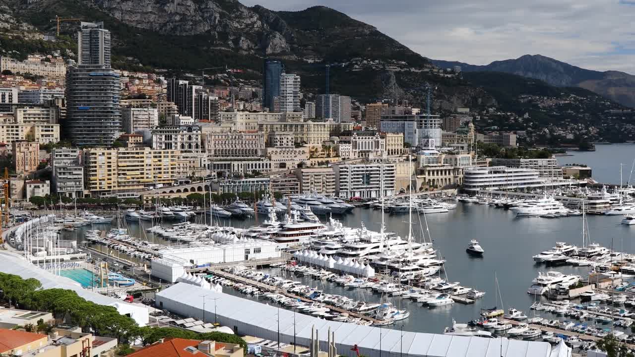 Aerial view of Monte Carlo showing luxury marina filled with yachts, elegant urban skyline, and mountain backdrop capturing wealth, architecture, and coastal charm of Monaco cityscape
