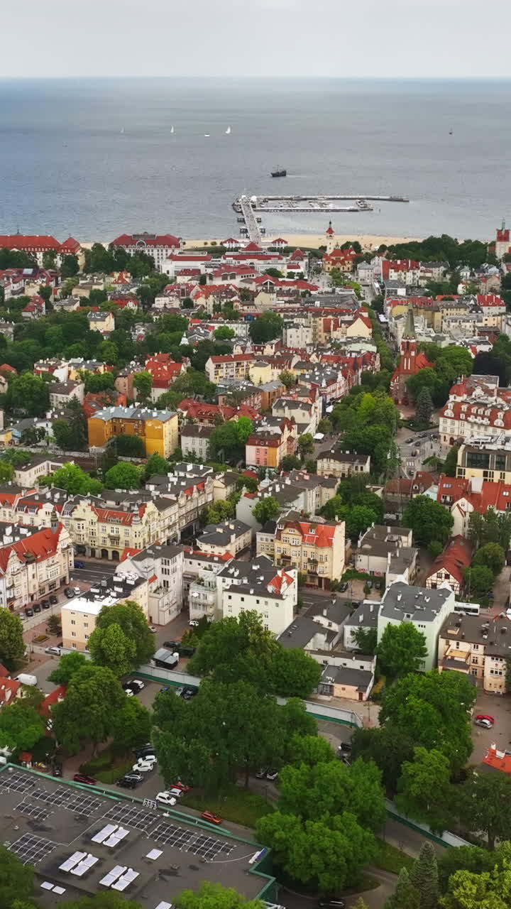 Plano vertical com drone filmando de trás para frente a paisagem urbana de Sopot, dia de verão na Polônia