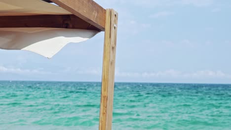 Part-of-Cabana-Sunbed,-with-beautiful-green-sea-on-the-background,-shallow-depth-of-field,-slow-motion