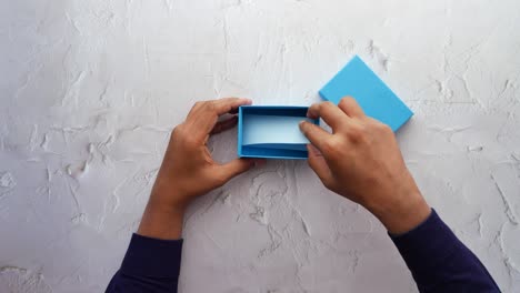 hands opening a light blue gift box