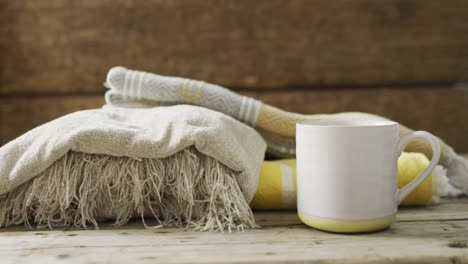 video of folded blankets and cup of tea on wooden background