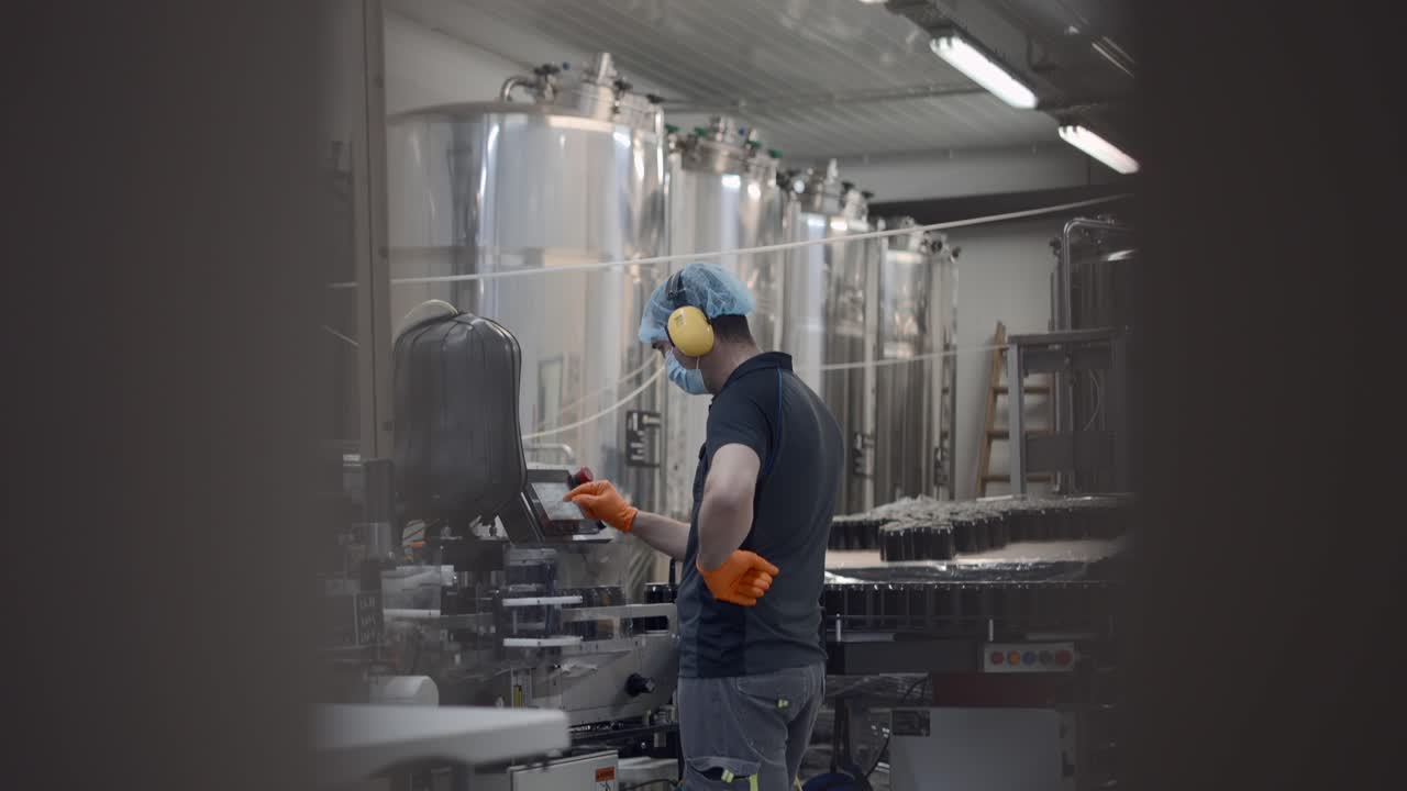 Worker operating bottling machine in a beverage factory