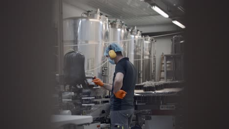 worker operating bottling machine in a beverage factory