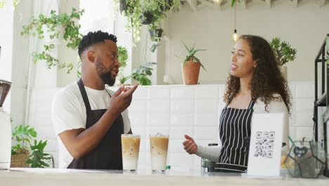 Happy-african-american-male-cafe-owner-and-biracial-female-barista-making-coffe-at-cafe