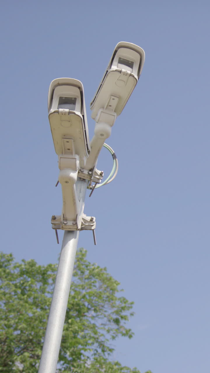 CCTV security cameras on pole doing surveillance of area, upwards zoom. Vertical