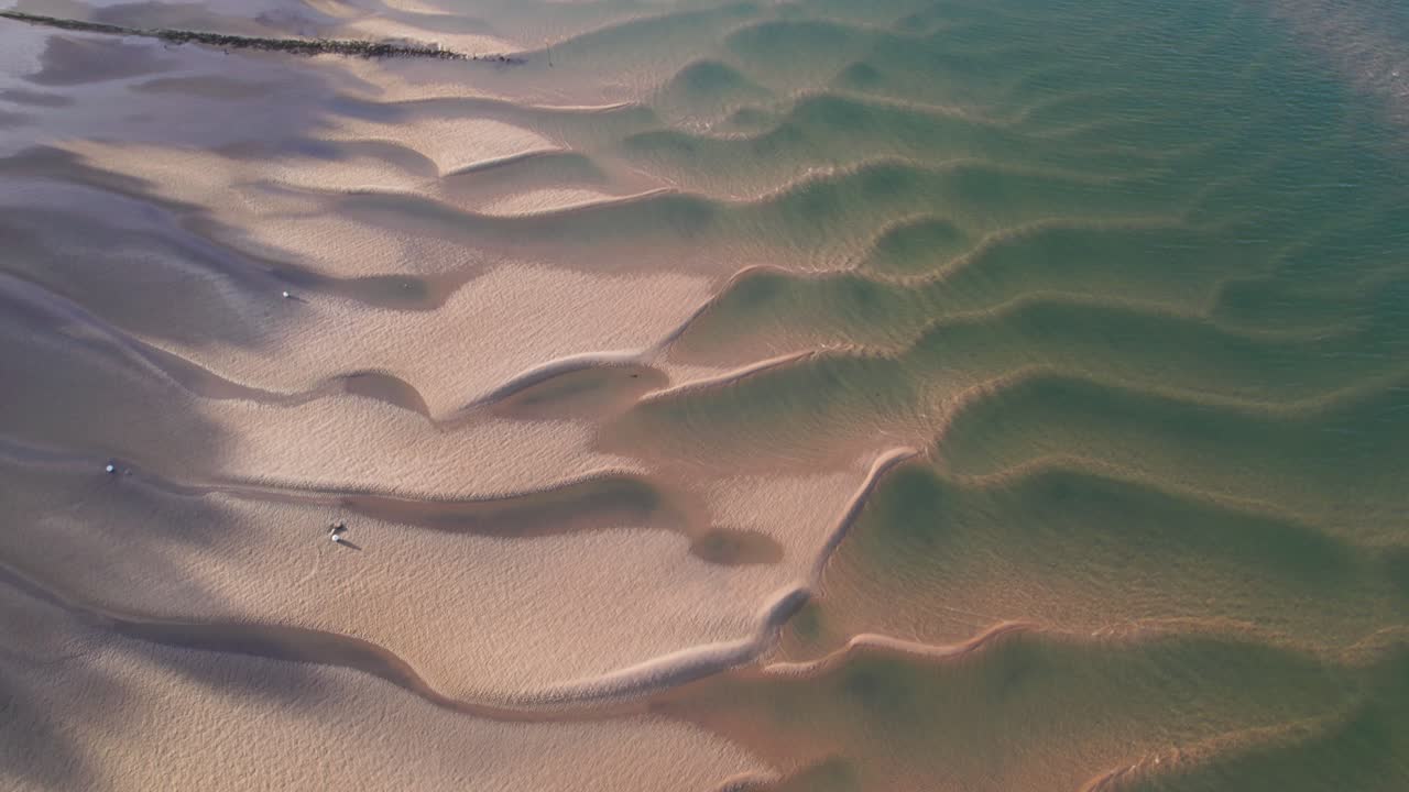 ondas de arena dejadas en la costa durante la marea baja en la playa desde arriba