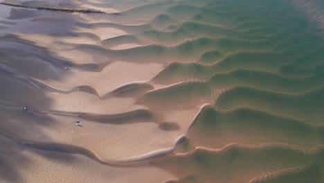 sand ripples left on the shoreline during low tide at the beach from above