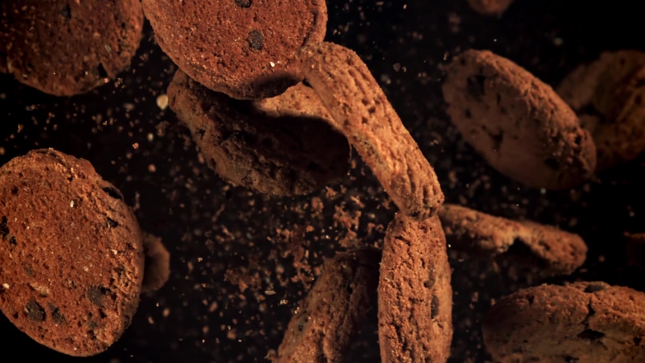 Deliziosi cookies al cioccolato che cadono al rallentatore con briciole
