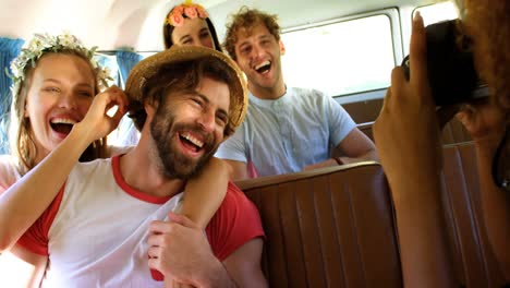 group of friends having fun in the van and a woman takes pictures