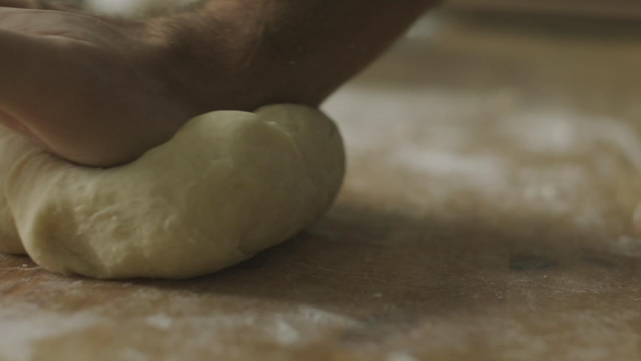 Hands Kneading Dough on Wooden Kitchen Table Dusted with Flour