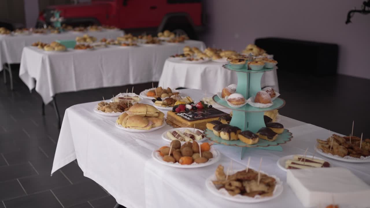 White tablecloth buffet with pastries, sandwiches, and sweets displayed on plates