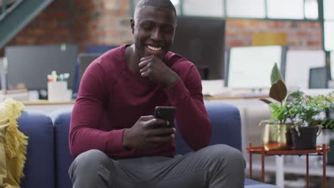 Happy-african-american-businessman-using-smartphone-at-office