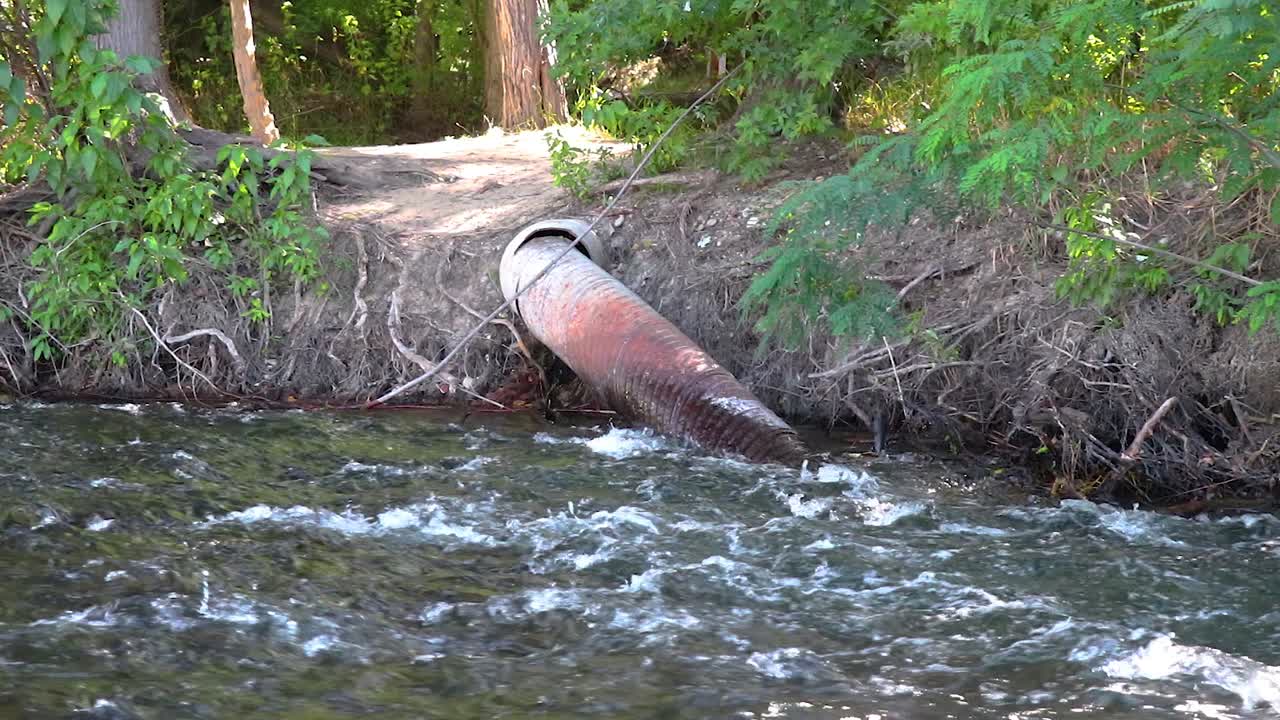 A Metal Irrigation Pipe IN A River Flowing Through The Forest 20 Second Slow Motion Video.