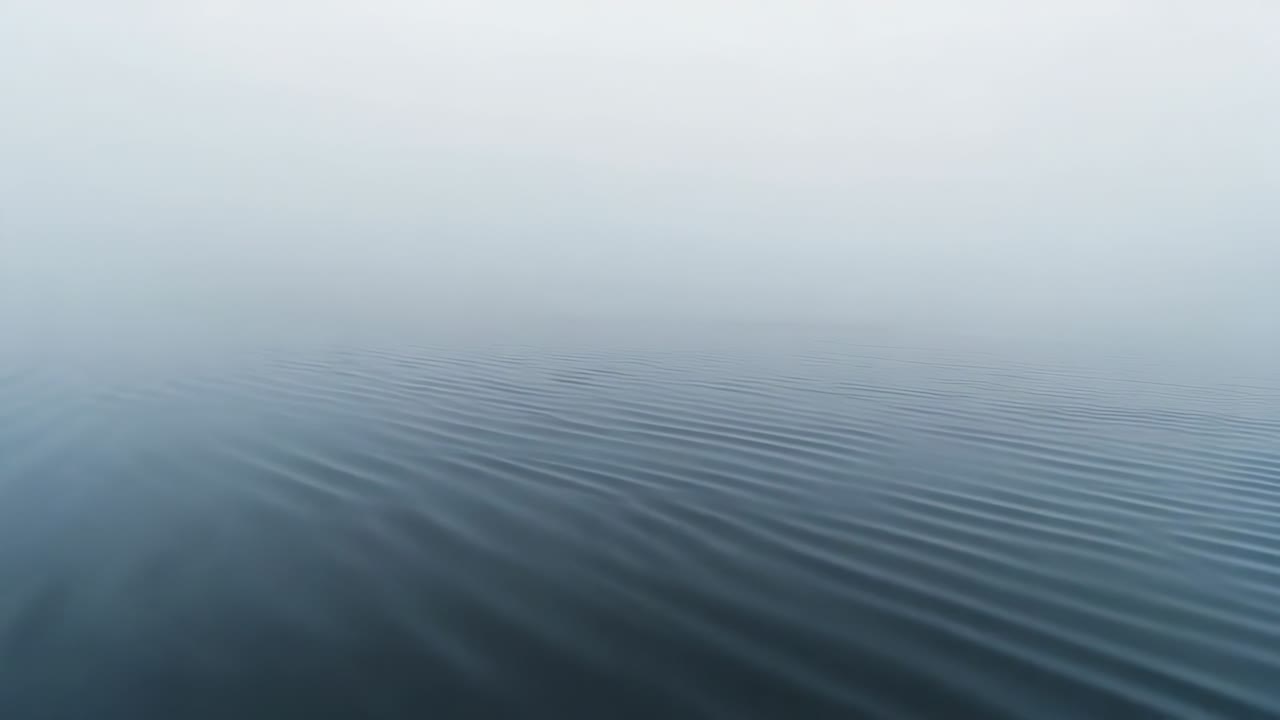 Showing open water forming gentle parallel ripples after light breeze at sea, fog obscuring horizon