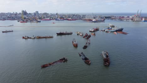 ship breaking area in montevideo bay outside port breakwater. partially sunken, rusty and broken shipwrecks stored side by side. environmental and oil pollution hazard. aerial view.
