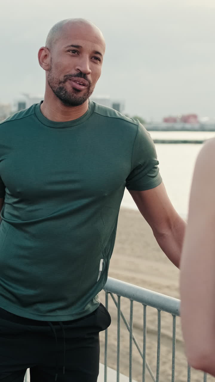 Uomo sorridente in abbigliamento sportivo che parla all'aperto vicino alla spiaggia
