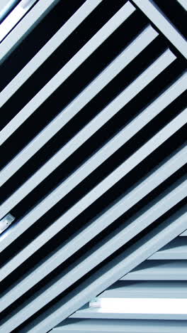non-standard decoration of the ceiling with white planks. long lamps with white light among the ledges. low angle view. vertical video