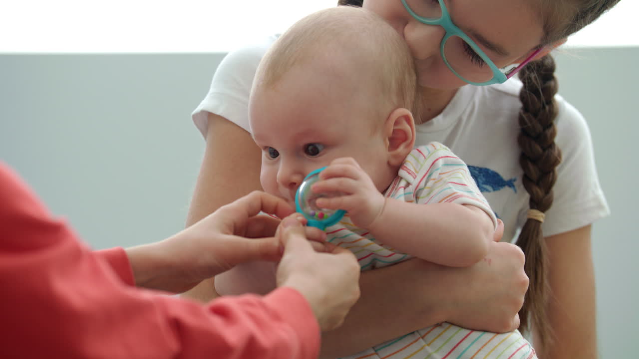 장난감과 함께 아기를 들고 있는 십대 소녀. 남동생을 들고 있는 여동생