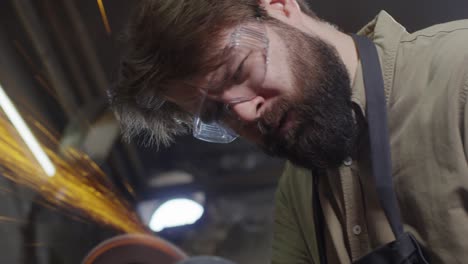 handsome worker polishing metal detail in smithy