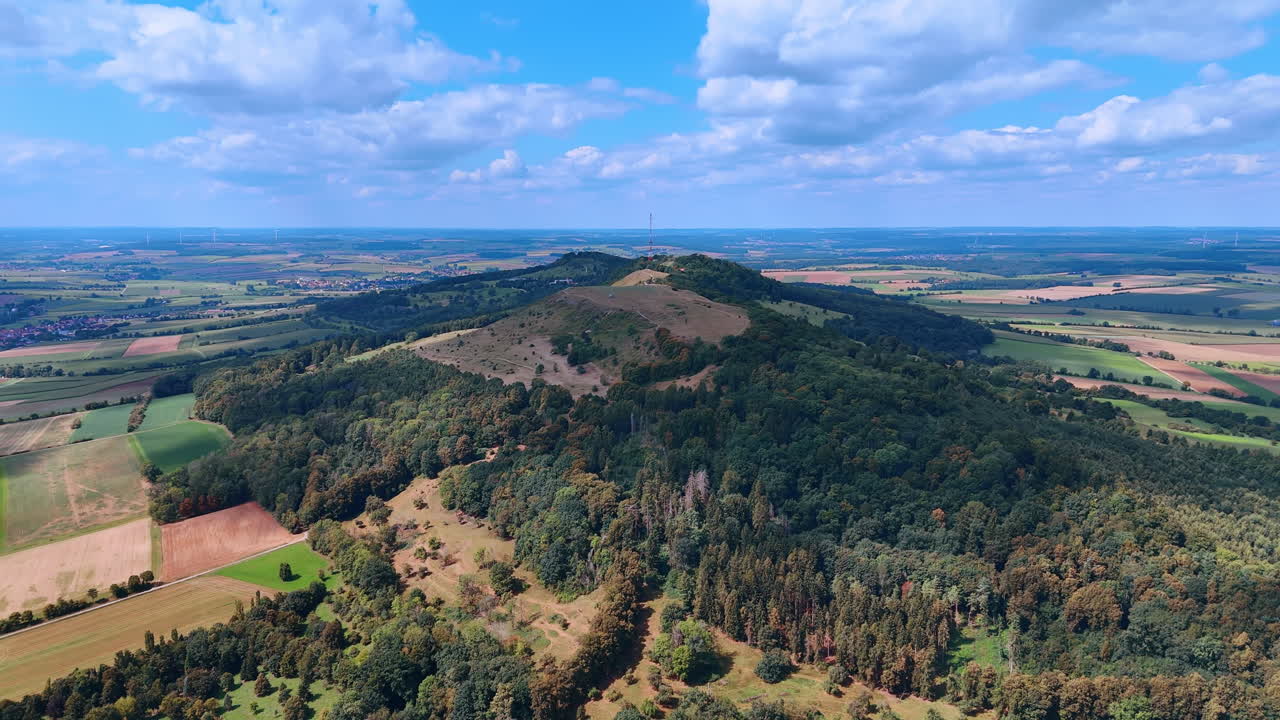 Luftfoto av Hesselberg-fjellet med et telekommunikasjonstårn. Naturskjønt luftfoto av den skogkledde fjelltoppen Hesselberg med en radiomast, omgitt av jordbruksland.
