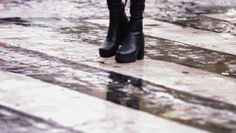 super slow motion footage of black high heel boots walking across a wet crosswalk in the rain