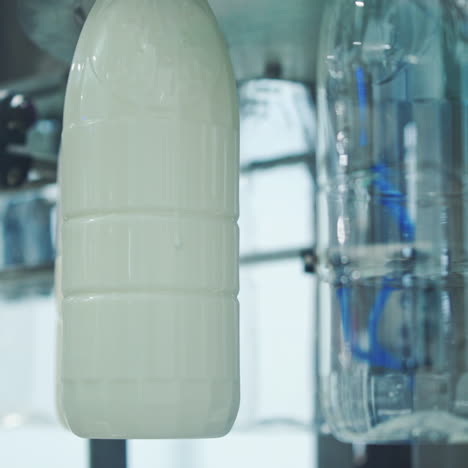bottles filling with milk by mechanical machine. upgraded technology in dairy factory. process of pouring milk into plastic bottles. close-up.
