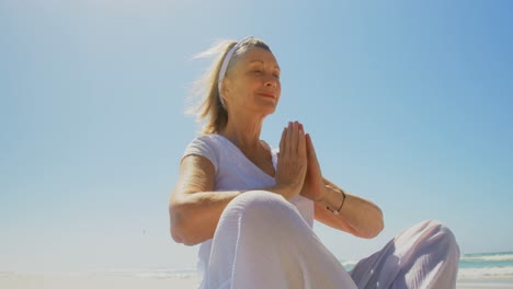 Low-Angle-Ansicht-Einer-Aktiven-älteren-Kaukasischen-Frau,-Die-Am-Strand-Yoga-Macht,-4k